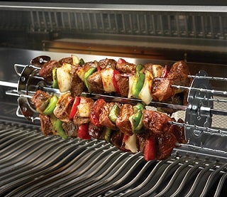 Several kebabs on a kebab scewer set over the BBQ grill